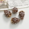 Detailed macro view of brown strawberry resin charms with white pearls and gold loops - Brown