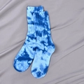 Blue tie-dye crew socks with cloud pattern on a gray fabric background - Blue