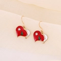 Macro shot of heart-shaped Christmas earrings with red enamel and a small green tree - Heart with Christmas Tree