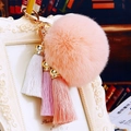 Detail of pink faux fur pompom and three-color tassel on a gold metal keychain - Pom Pom + Three Tassels / Pink
