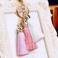 Detailed view of golden keychain with silk tassels in white, pink, and light purple - Pink White Gradient