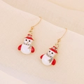 Macro detail of snowman earrings with red hat and scarf on beige textured fabric - Drip Oil Snowman with Star