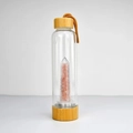 Detail of glass energy bottle featuring natural pink crystals and bamboo lid with rope handle - Pink