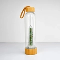 Close-up of glass water bottle with bamboo lid and green aventurine crystal chips - Green