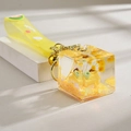 Detail eines kreativen Haus-Schlüsselanhängers mit gelbem Silikonband und Goldglitzer - Regenbogen Seil+Haus+Glocke / Zitronengelb