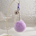 Dettaglio di un portachiavi pompon viola con perle e ciondolo a cuore camelia - Catena con Gancio + Palla di Peluche a Cuore [Include Linguetta per Cellulare] / Viola