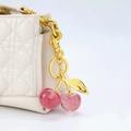 Portachiavi ciliegia rosa glitterata con foglie dorate su borsa trapuntata bianca - Ciliegia rosa