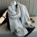 Elegant silver gray gradient silk scarf styled with a camellia brooch on a mannequin - Gray