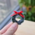 Mini ghirlanda di Natale con brina bianca e fiocco rosso tenuta in mano per scala - Verde petrolio