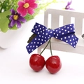 Cute cherry hair clip with dark blue polka dot bow and red cherry charms on bench - Blue White Polka Dot