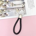 Detail van zwarte gevlochten leren sleutelhanger met zilveren metalen ring en musketon - Zwart