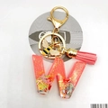 Macro shot of resin letter W keychain with pink glitter, bee charm, and suede tassel detail - Letter W Bee Keychain