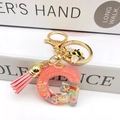 Macro view of pink glitter resin letter G keychain with honeybee and leather tassel - Letter G Bee Keychain
