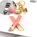 Detailed close-up of pink resin letter X keychain with glitter, tassel, and bee charm - Letter X Bee Keychain