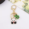 Close-up of golden metal panda keychain with green bamboo and a red heart pendant - Panda Holding Heart and Bamboo