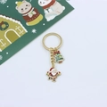 Detail of enamel Santa Claus and Christmas tree pendants on a golden metal keychain - Running Santa & Christmas Tree