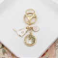 Detail of golden enamel keychain with cute cat, cherry blossom and pink paw charms - Cat & Bamboo Leaves