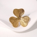 Anello aperto a trifoglio dorato minimalista con dettagli testurizzati su pelle bianca - Oro