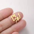Polished gold stainless steel Arabic calligraphy pendant held by hand for scale - Gold Climber