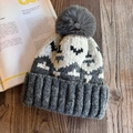 Macro detail of wave patterned knit beanie with a soft faux fur pompom on wooden surface - M (55-59cm) / Gray