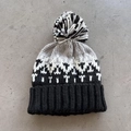 Macro view of knit texture with geometric jacquard pattern and a soft bicolor pom-pom - One Size / Black