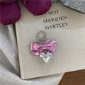 Detail von rosa Metallbogen und Silberherz-Anhänger auf Vintage-Büchern für Accessoires - Stil 1 Fuchsia Schleife Herz Anhänger
