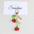Cute cherry resin keychain with green leaves and a golden handmade tag on a gift card - Double Cherry Pendant