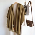 Detail shot of a moss green cashmere-like scarf with tassels on a white coat - Mustard Yellow / 200cm