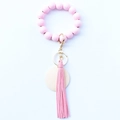 Pink wooden bead bracelet keychain with leather tassel and gold ring on white background - Pink