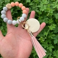 Silicone bead keychain bracelet with wooden hexagon bead and pink tassel held by a hand - Pink Orange Marble Color (款1)