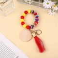 Détail du porte-clés en perles de silicone avec médaillon en bois et pompon rouge - Tourbillon Arc-en-ciel Rouge Jaune