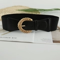 Elastic black waist belt with golden woven texture buckle on a decorative magazine - Black