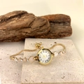 Detail of gold heart link quartz watch with rhinestones on a decorative stone base - Gold