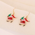 Detailed macro of Santa Claus earrings with a green Christmas tree and red enamel finish - Santa with Christmas Tree