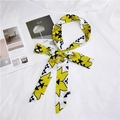 Detail of yellow and black geometric floral silk twilly scarf with angled ends on fabric - Four-Leaf Clover