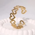 Bracciale rigido a cuore in acciaio inossidabile dorato su piatto bianco decorato - Oro