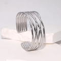 Minimalistischer silberner Edelstahl-Armreif in geflochtenem Design auf weißem Podest - Silber