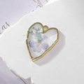 Makroaufnahme von Herzanhänger aus Harz mit echten lila Blumen und goldenem Metallrahmen - 4-Schleierkraut Blaue Blume