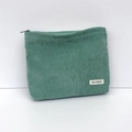 Detail of green corduroy makeup bag featuring soft ribbed texture and a branded fabric label - Grass Green