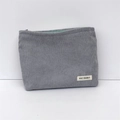 Detail view of grey corduroy makeup bag with mint green zipper and branded label - Gray