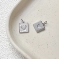 Détail macro de pendentifs cœur plaqués or avec incrustations en nacre sur plateau - Cœur Argenté / Pièce Unique