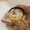 Coletero metálico dorado con textura de lava irregular y banda elástica sobre piedra - Estilo 1 (Textura de lava)