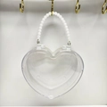 Dettaglio di una borsa trasparente a forma di cuore con elegante manico in perle bianche - Bianco