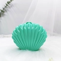 Close-up of green shell-shaped storage box on white fur with soft nature background - Green