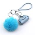 Close-up of blue faux leather mini bag and fluffy fur pompom keychain with metal hardware - Blue