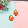 Vista dettagliata di due ciondoli a fragola rossi con foglie verdi e bordi dorati - Fragola 2