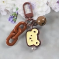 Detailansicht einer braunen Schlüsselkette mit gelbem Bärenanhänger und kleiner Glocke - 5126-4 Brauner Bär
