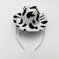 Close-up of black and white cow print mini cowboy hat headband for party accessories - Denim / Cow Print