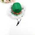 Close-up of a green pet cowboy hat with red ribbon, gold buckle and white feather trim - Feather Christmas Hat / Green