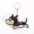 Close-up of a handmade leather puppy keychain in black and beige with red collar - Black Dog